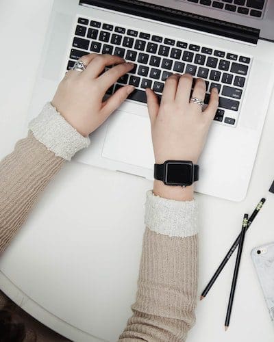 female hands typing on a macbook pro at a desk