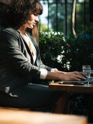 Image of a women in a business suit working at computer in a natural environment